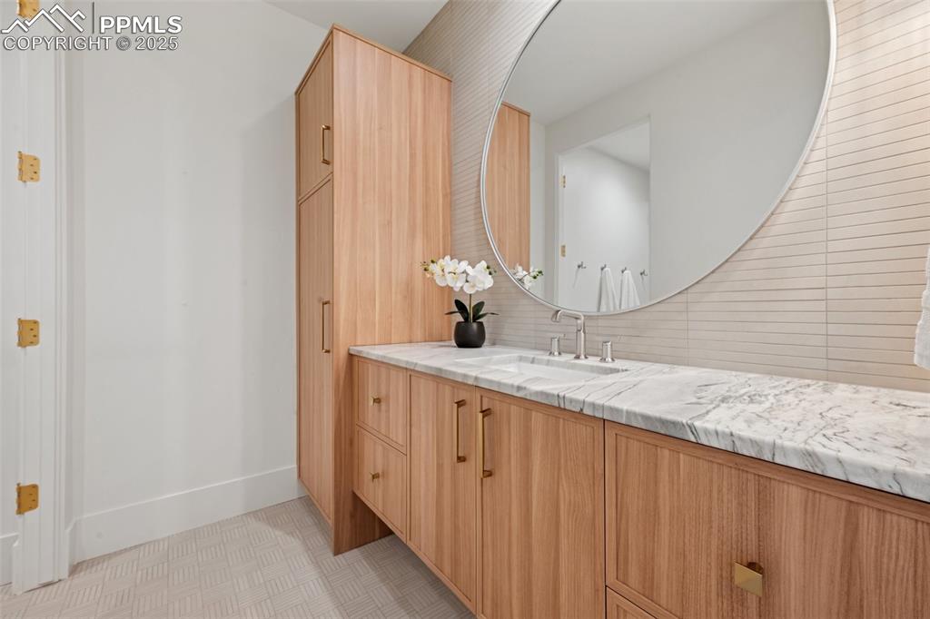 Image 42 of 50: Bathroom featuring vanity and tasteful backsplash