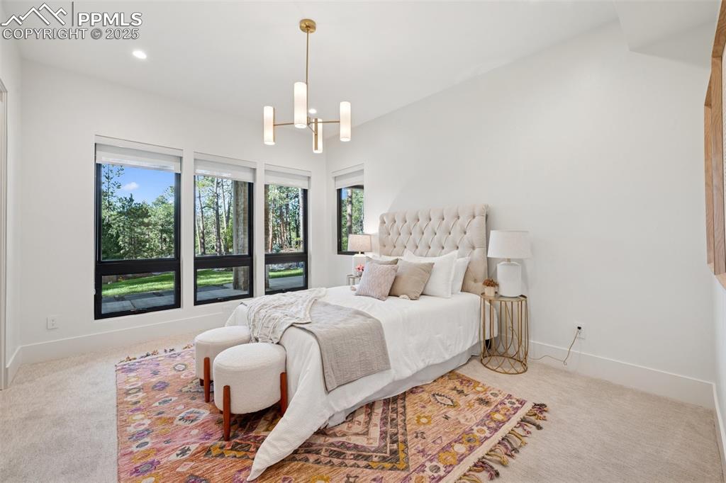 Image 43 of 50: Carpeted bedroom with a chandelier and recessed lighting