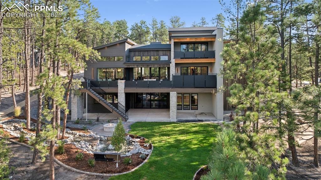 Image 44 of 50: Rear view of property featuring a balcony, a patio area, stairs, a yard, an