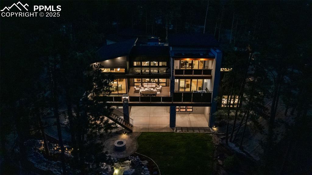 Image 50 of 50: Back of house at twilight featuring a balcony, a yard, and stairway