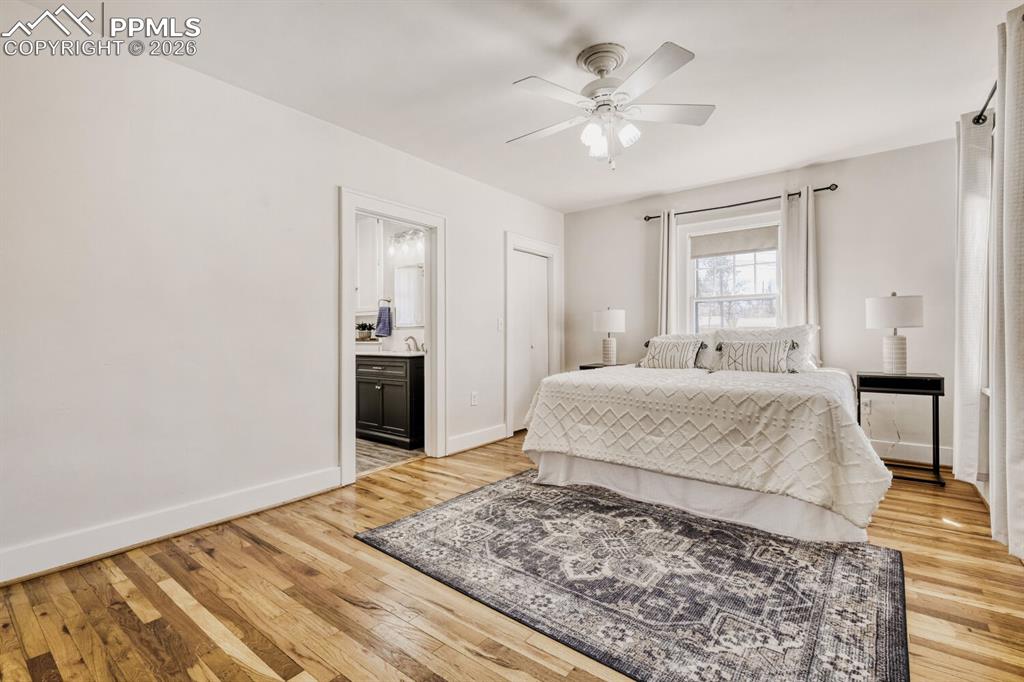 Image 13 of 34: Bedroom featuring light wood-style floors, ceiling fan, and ensuite bathroo