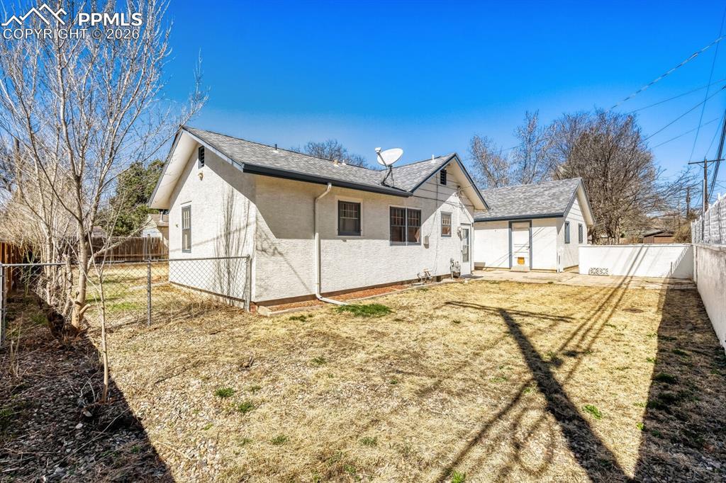 Image 27 of 34: View of side of property with a fenced backyard, a shingled roof, and stucc