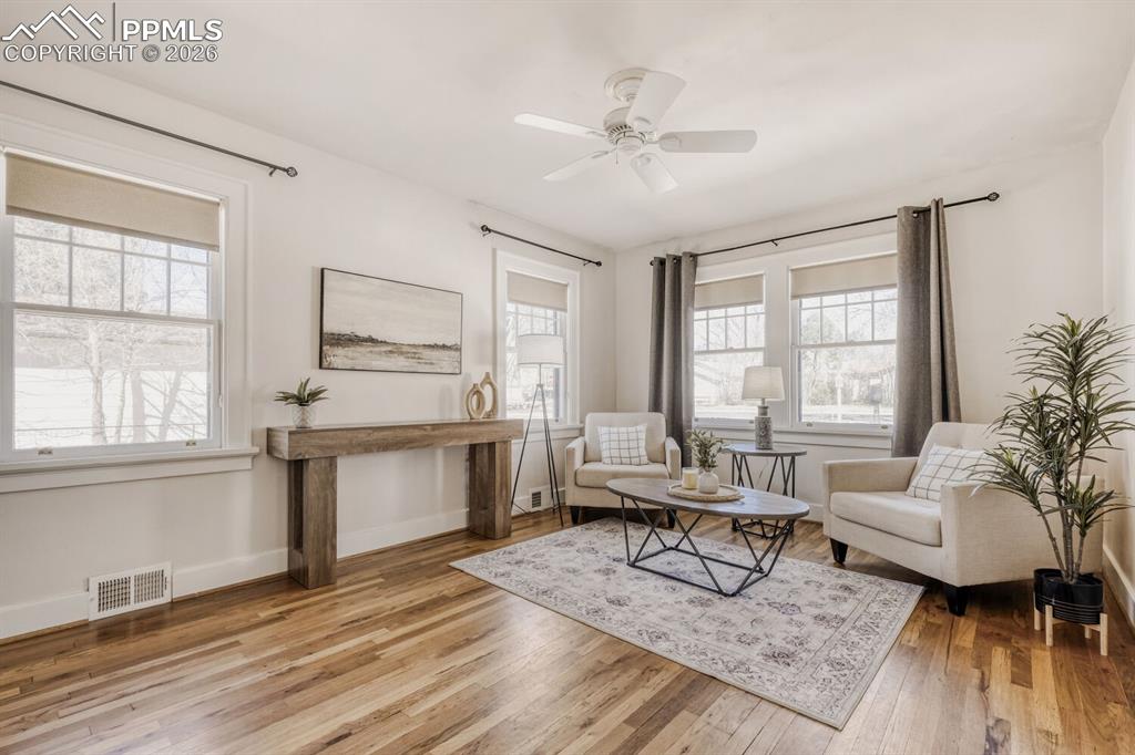 Image 4 of 34: Living area with light wood-style floors and a ceiling fan