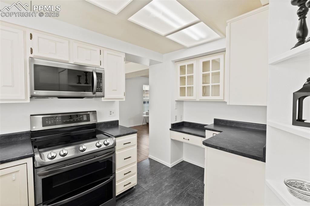Image 10 of 31: Kitchen featuring appliances with stainless steel finishes, dark countertop