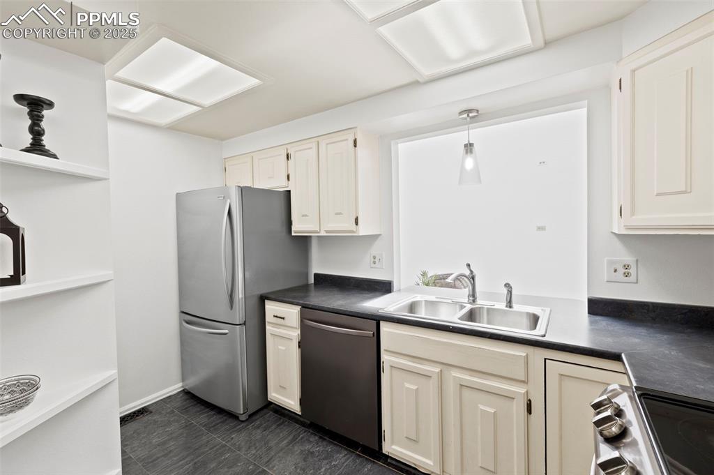 Image 11 of 31: Kitchen with appliances with stainless steel finishes, dark countertops, ha
