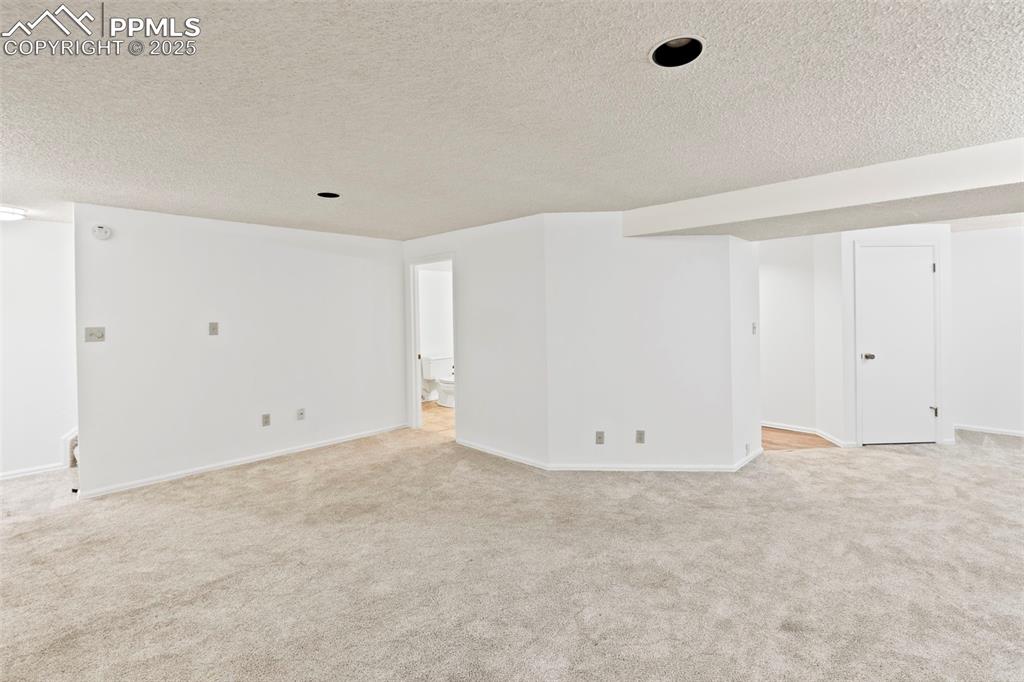 Image 23 of 31: Spare room featuring a textured ceiling and light carpet