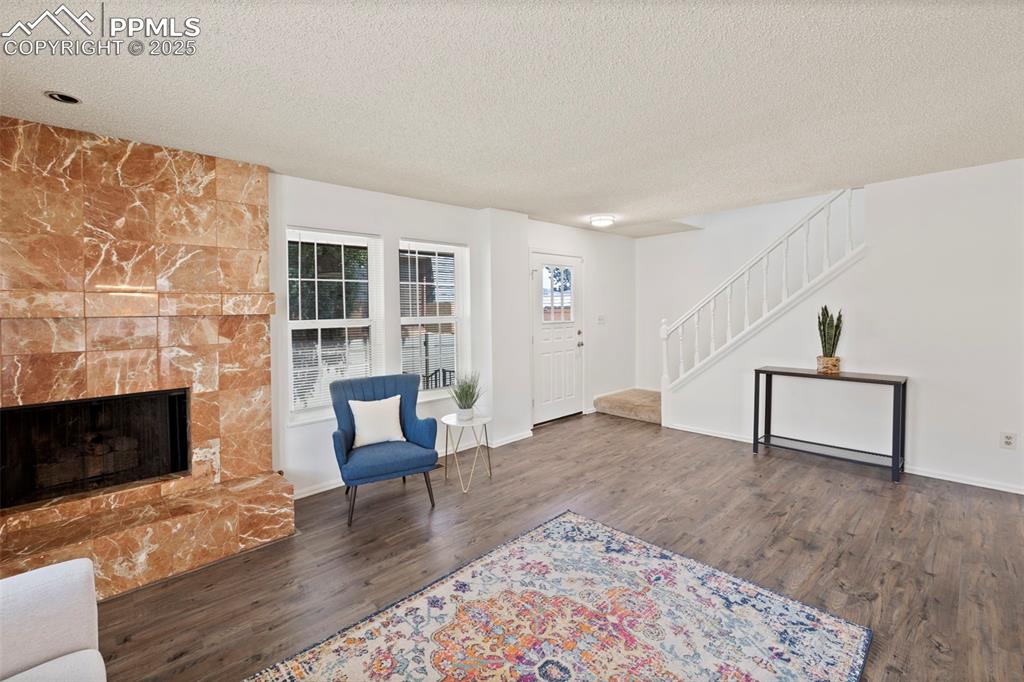 Image 5 of 31: Living area featuring stairway, a textured ceiling, dark wood finished floo