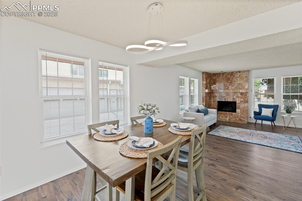 Image 7 of 31: Dining space featuring dark wood-type flooring, a fireplace, and a textured