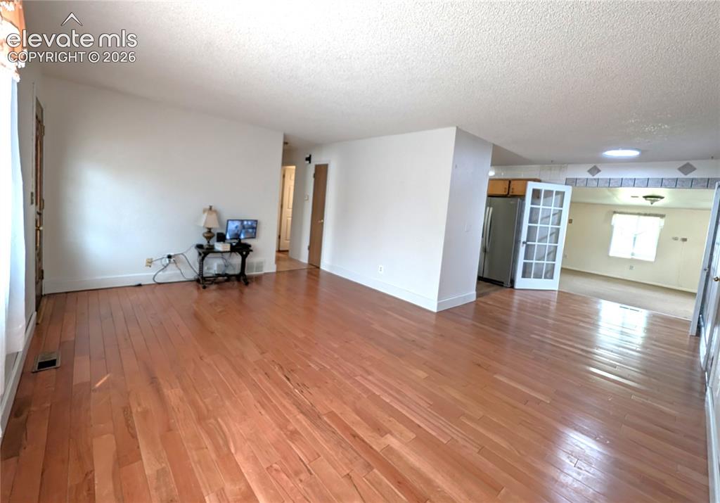 Image 4 of 16: Living room, wood floors, looking towards kitchen, addition room, hallway t