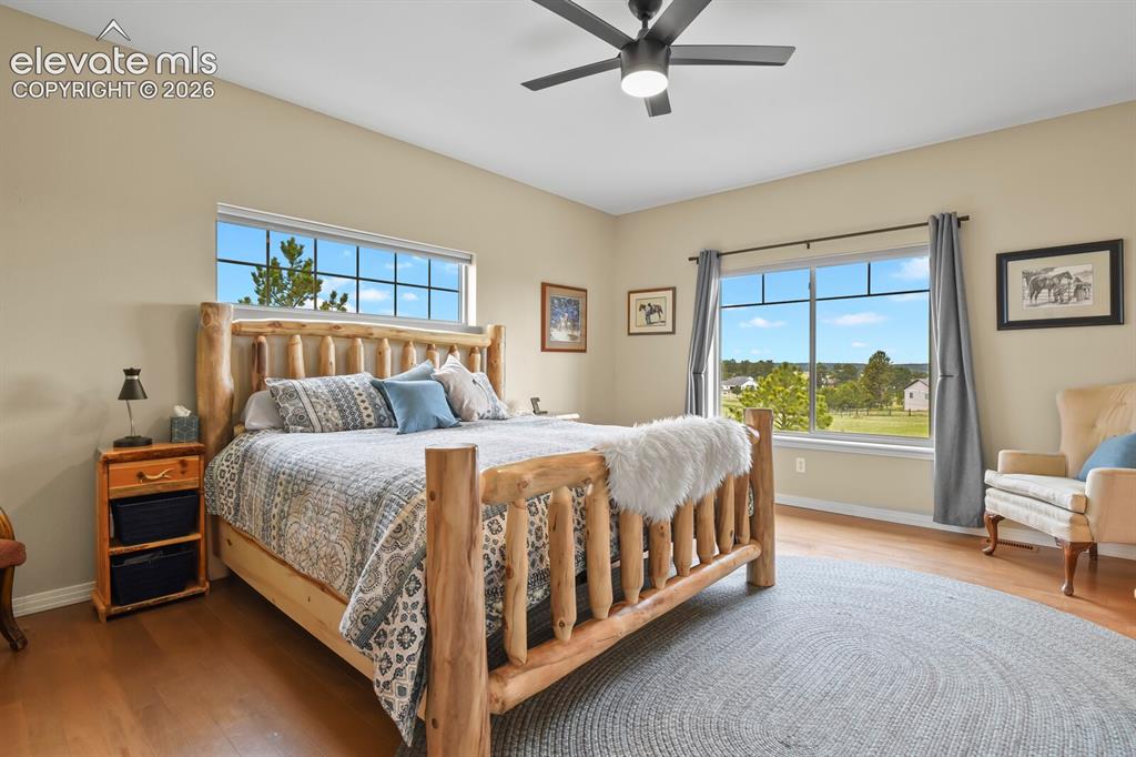 Image 14 of 45: Spacious primary suite with hardwood flooring, large windows, and peaceful 