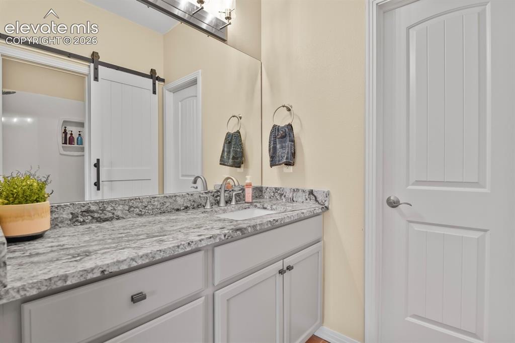 Image 16 of 45: One of two en-suite primary baths featuring slab granite vanity, updated fi