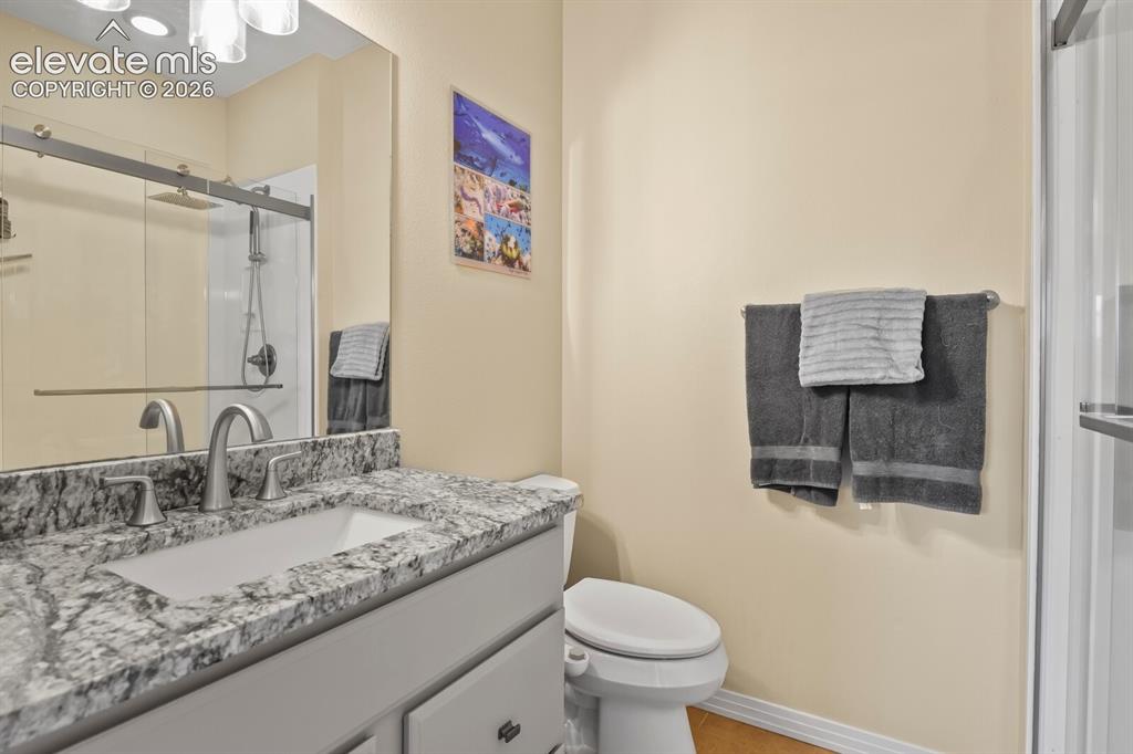 Image 18 of 45: Second primary en-suite bath featuring slab granite vanity, updated fixture
