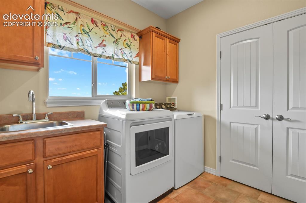 Image 24 of 45: Functional laundry room with utility sink, upper cabinetry, storage closet,