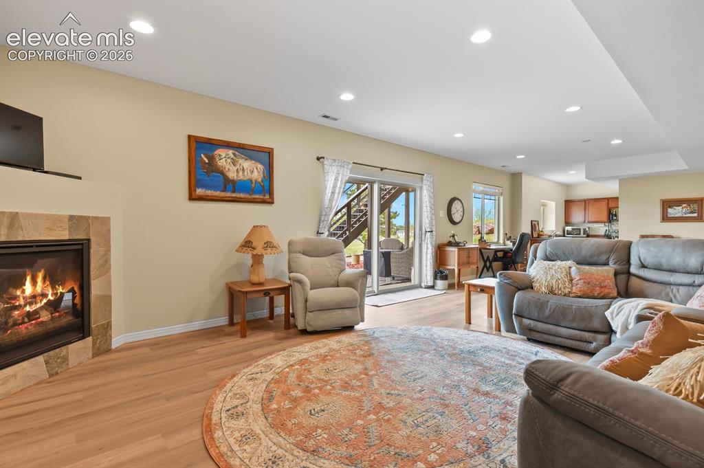 Image 25 of 45: Spacious recreation room with fireplace, updated flooring, and inviting gat