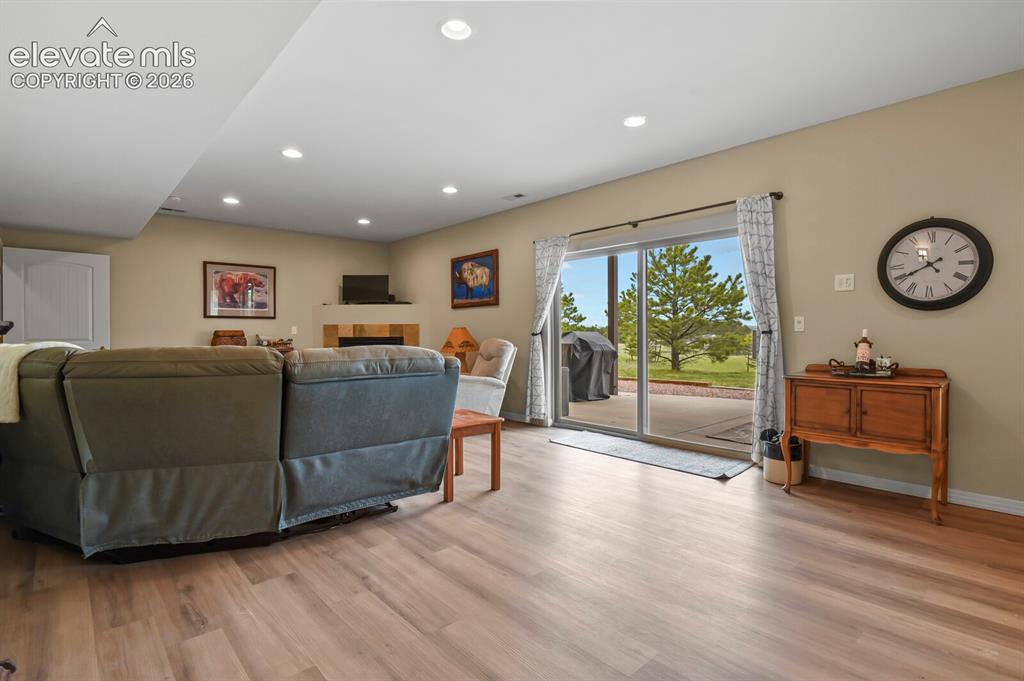 Image 26 of 45: Walkout recreation room with updated flooring, abundant natural light, and 