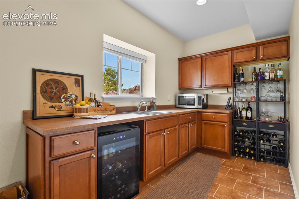 Image 27 of 45: Convenient lower-level wet bar with cabinetry, counter space, and ideal set