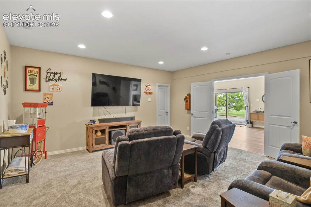 Image 29 of 45: Comfortable lower-level media space with natural light and walkout access t