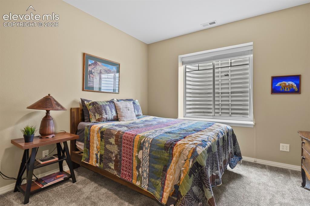 Image 32 of 45: Comfortable lower-level bedroom with natural light, neutral finishes, and c