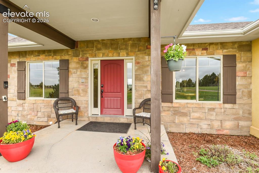 Image 5 of 45: Welcoming covered front porch with stone accents and inviting entry.