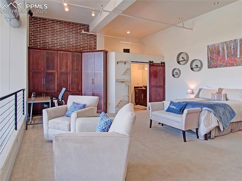 Image 18 of 32: Bedroom featuring a barn door, light colored carpet, connected bathroom, br