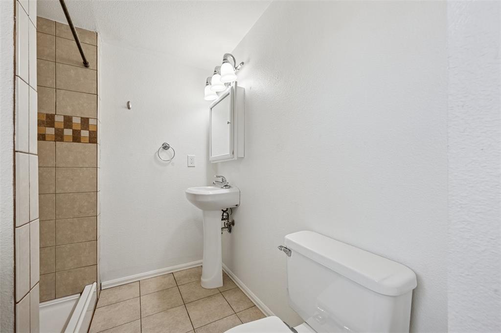 Image 25 of 33: Full bathroom with light tile patterned floors and a shower stall