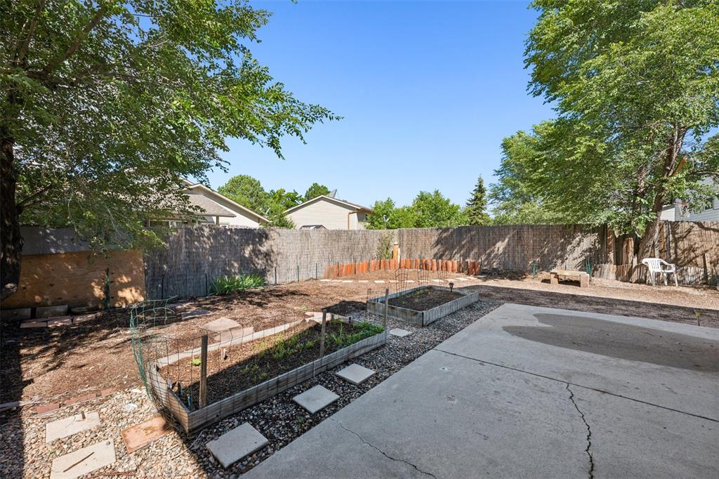 Image 30 of 33: Fenced backyard with a garden and a patio area