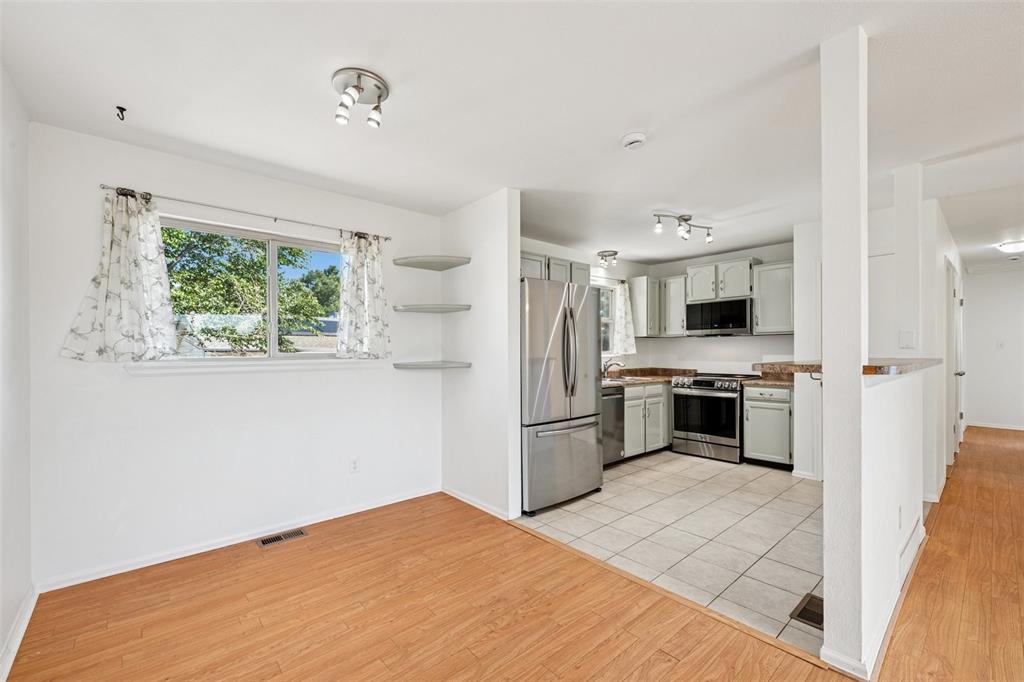 Image 6 of 33: Kitchen with open shelves, stainless steel appliances, light wood-style flo