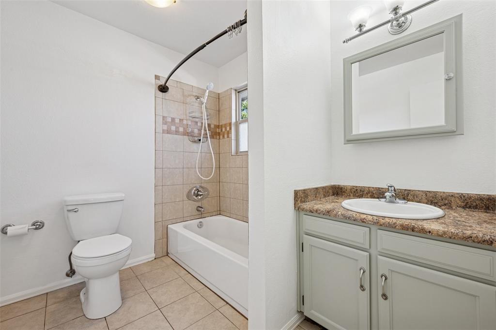 Image 7 of 33: Full bathroom featuring vanity, tub / shower combination, and light tile pa
