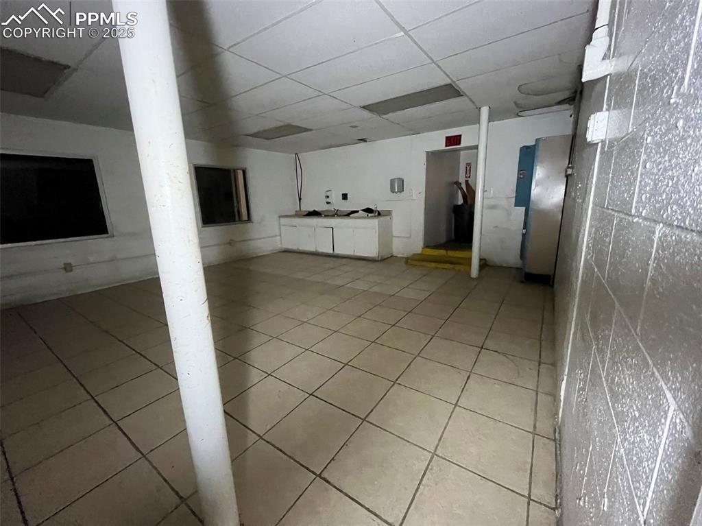 Image 13 of 23: Basement with a paneled ceiling and light tile patterned floors