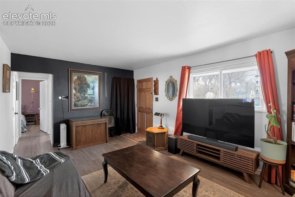 Image 10 of 19: Wood-finish flooring throughout, a white ceiling, and a prominent window