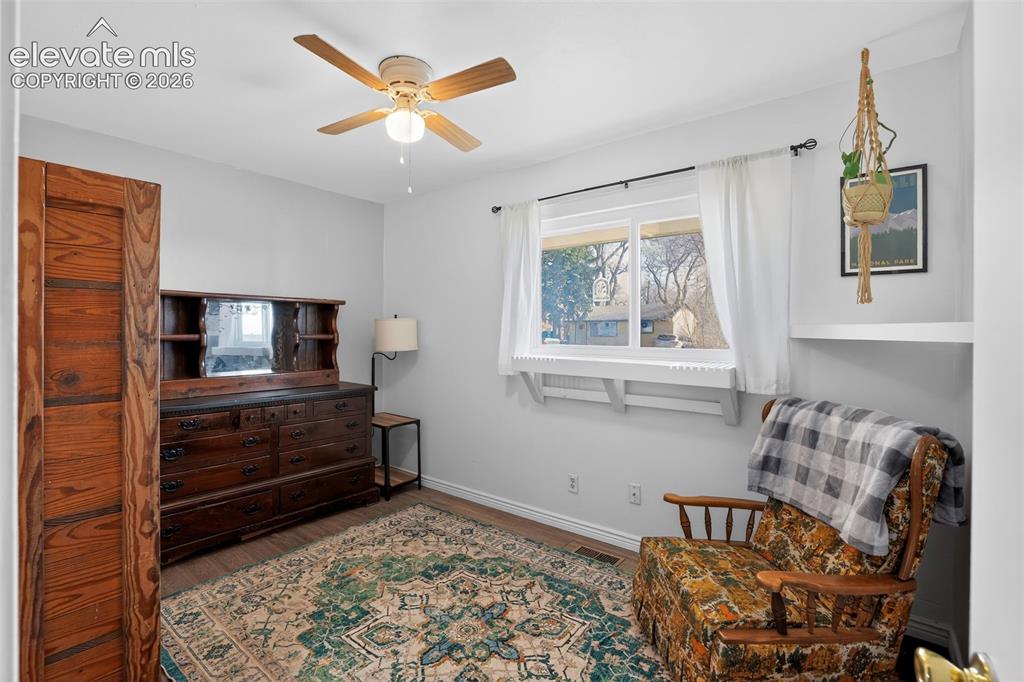Image 14 of 19: Wood-finish flooring, ceiling fan, and large window with white trim