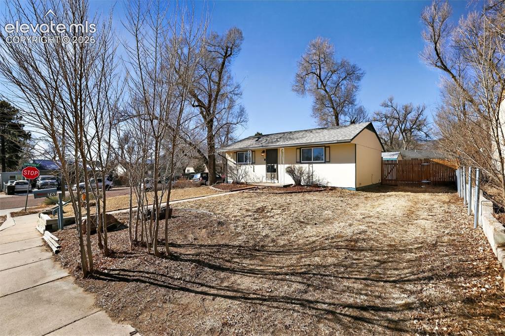 Image 2 of 19: Single-story residence with light-colored siding, a dark roof, and a fenced