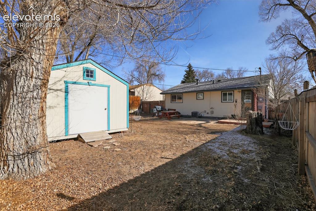Image 6 of 19: Backyard featuring a detached storage shed, a wood fence, and a rear stucco