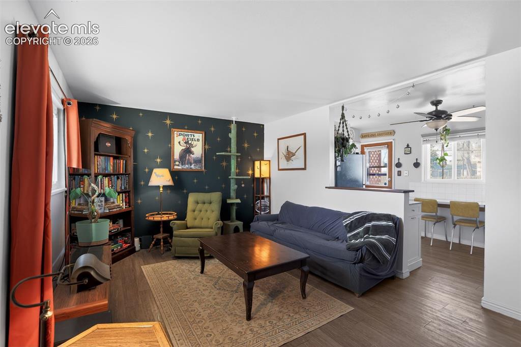 Image 9 of 19: Open concept living space with wood-finish flooring, a built-in bookshelf, 