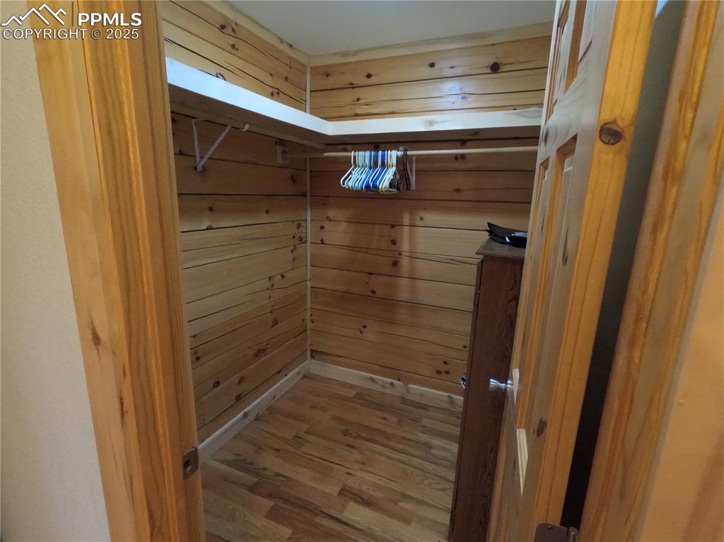 Image 10 of 23: Walk in closet with wood finished floors