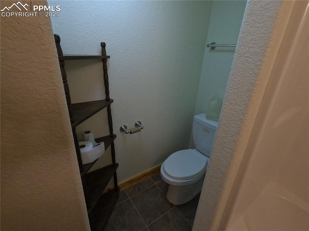 Image 18 of 23: Bathroom with a textured wall and dark tile patterned flooring