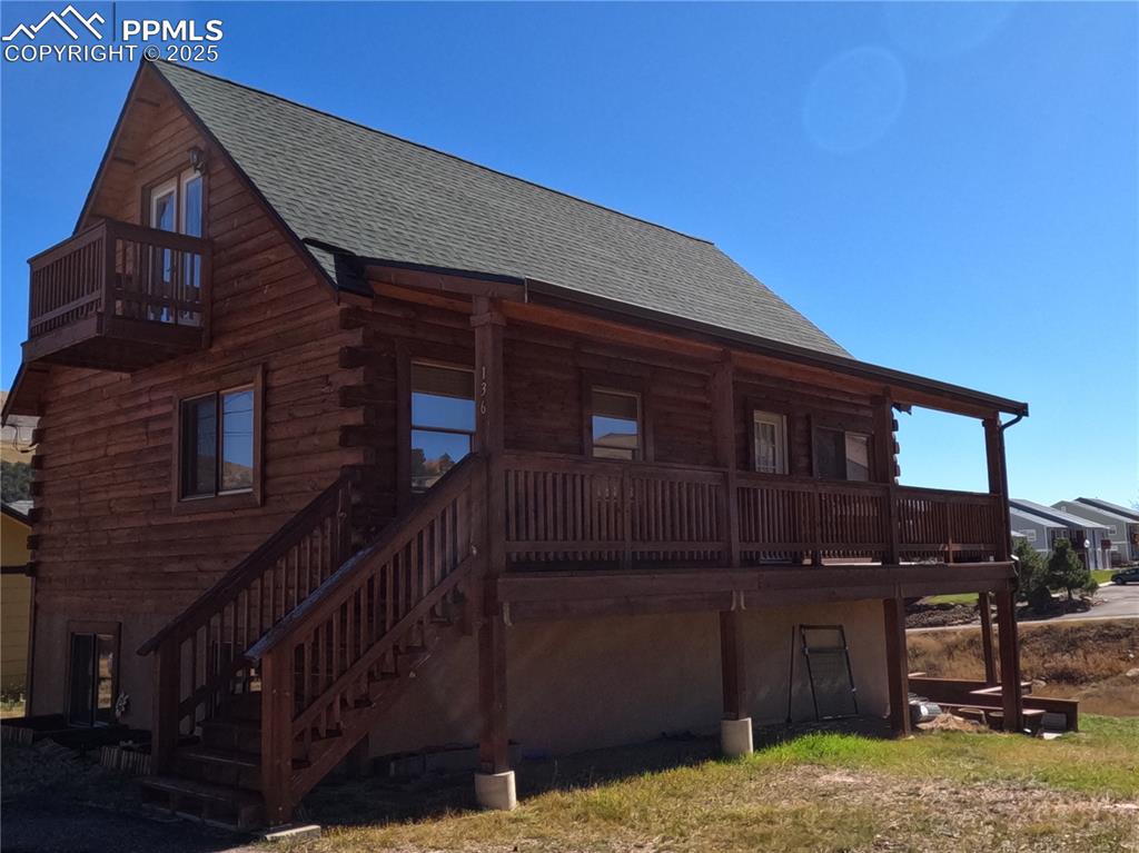 Image 2 of 23: View of side of property with roof with shingles, log siding, and a porch