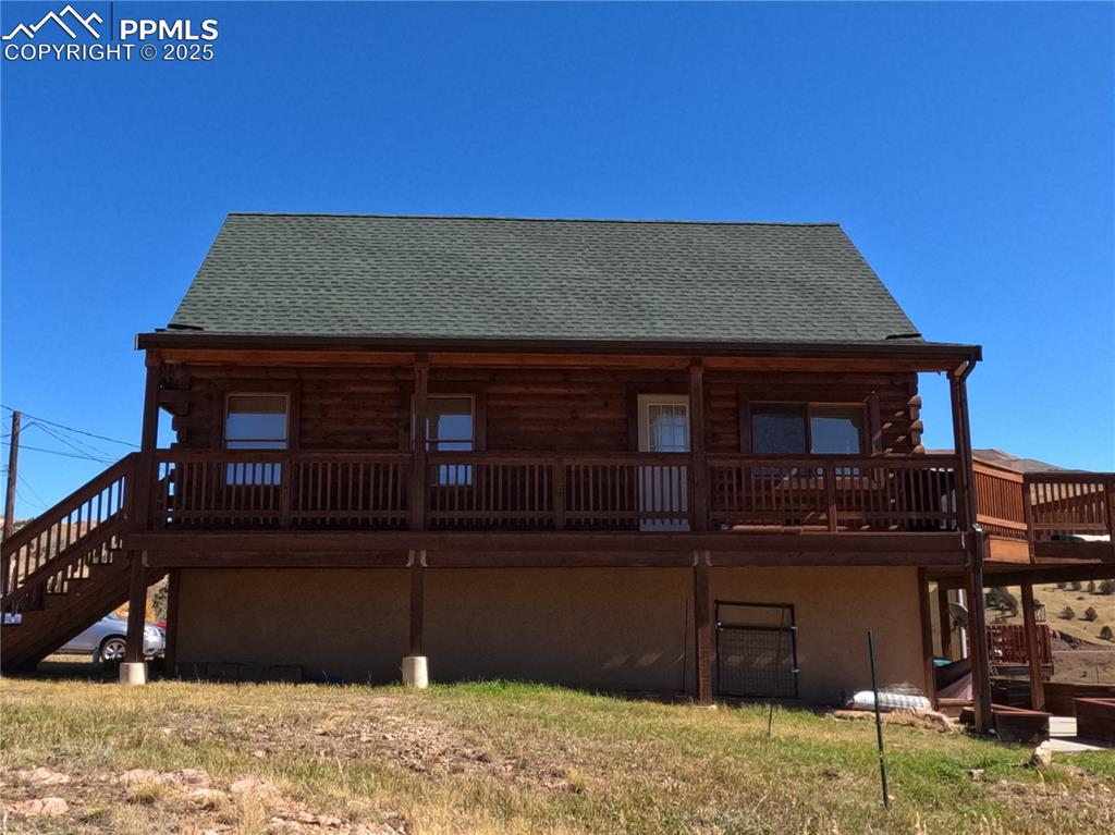 Image 3 of 23: Rear view of house featuring stairway, log siding, roof with shingles, and 