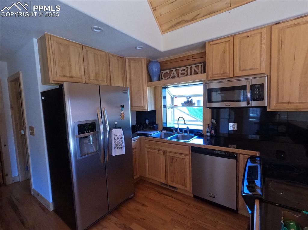 Image 8 of 23: Kitchen with appliances with stainless steel finishes, dark wood-style floo