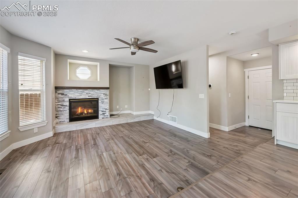 Image 13 of 39: Unfurnished living room with light wood-type flooring, a ceiling fan, a sto