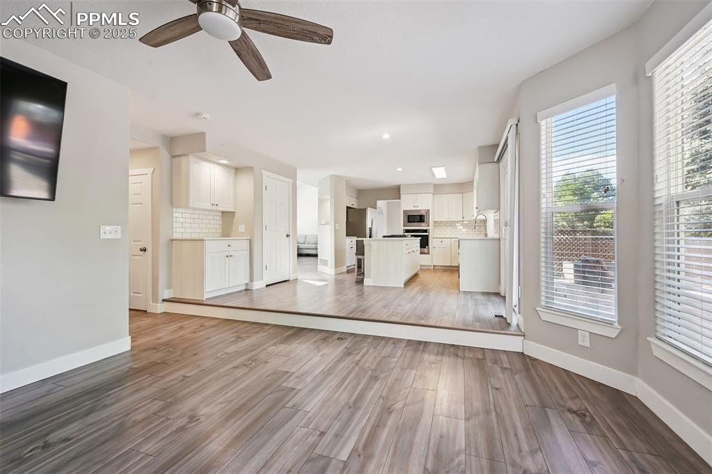 Image 15 of 39: Unfurnished living room with light wood-style floors, a ceiling fan, and re