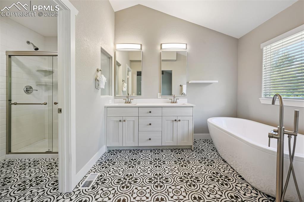 Image 19 of 39: Full bathroom featuring a shower stall, a soaking tub, double vanity, light