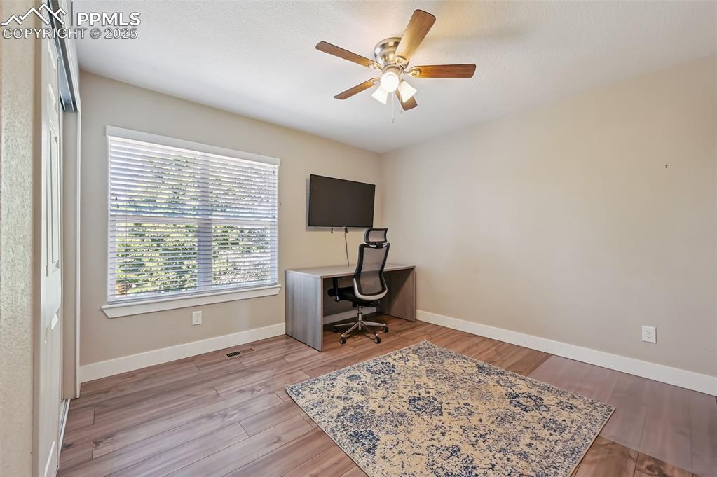 Image 22 of 39: Office space with light wood-style floors and ceiling fan