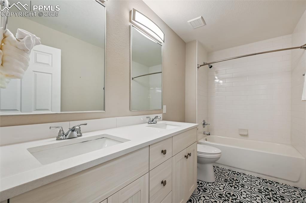 Image 28 of 39: Bathroom with shower / bath combination, double vanity, and light tile patt