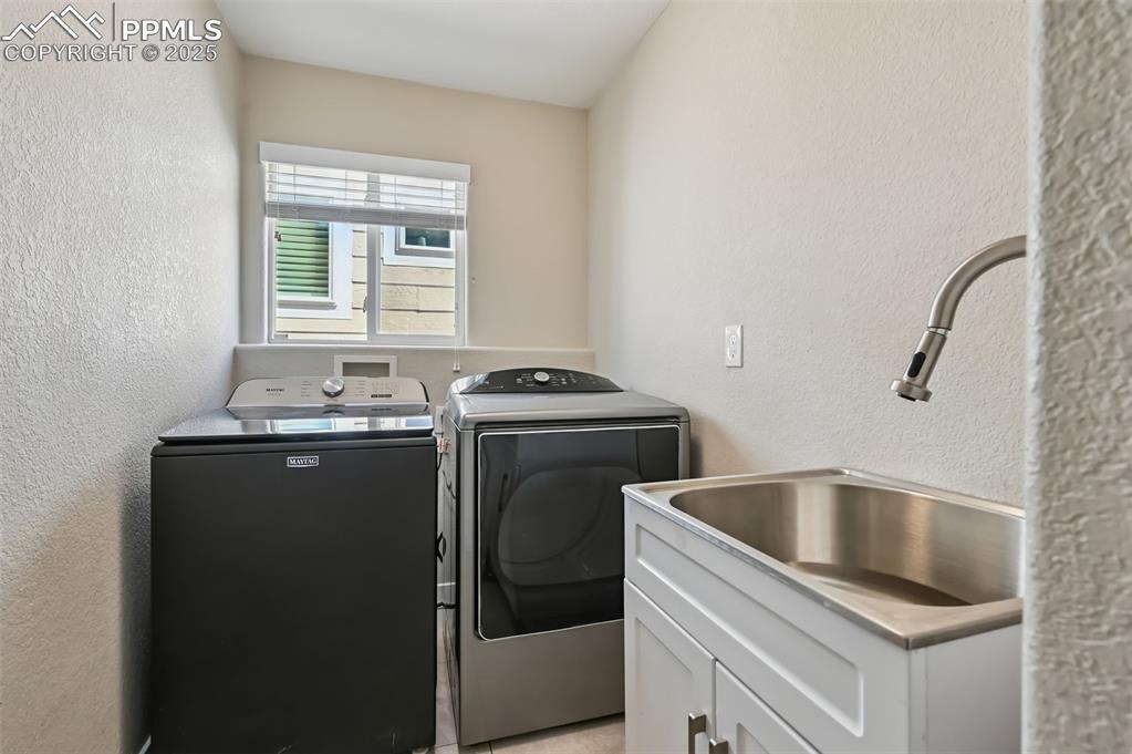 Image 29 of 39: Laundry area featuring a textured wall and washer and clothes dryer