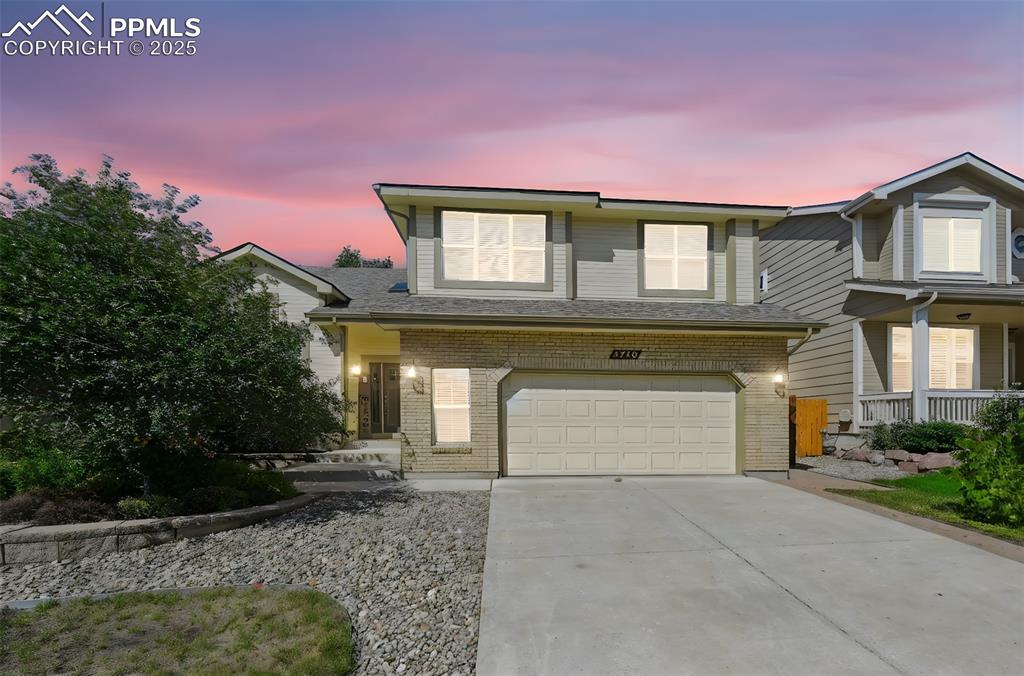 Image 3 of 39: Traditional home with driveway, brick siding, covered porch, and an attache