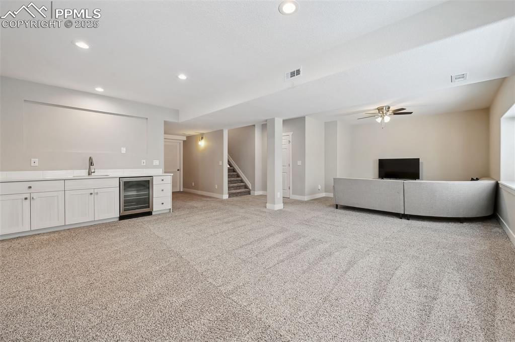 Image 32 of 39: Unfurnished family room featuring recessed lighting, light carpet, beverage