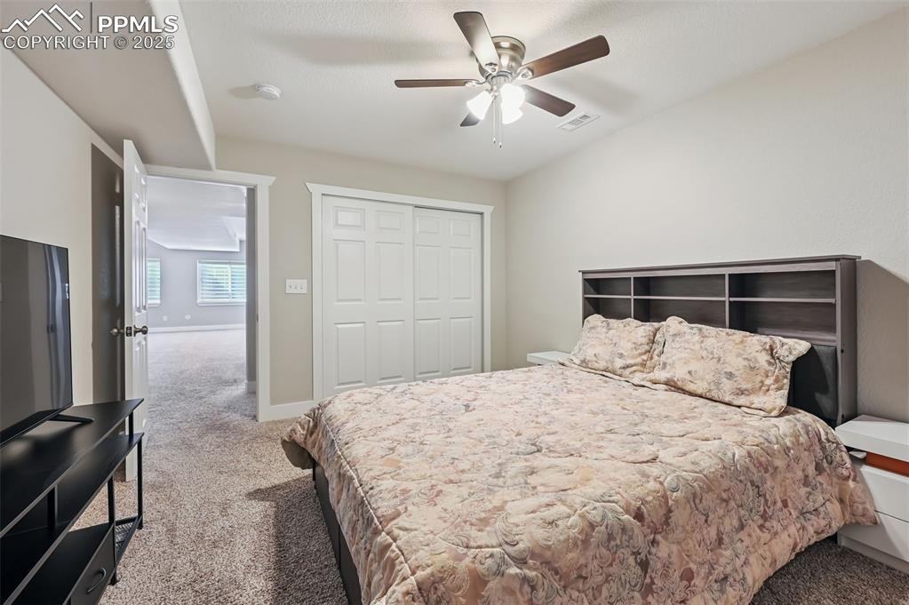 Image 34 of 39: Bedroom with light carpet, a closet, and a ceiling fan