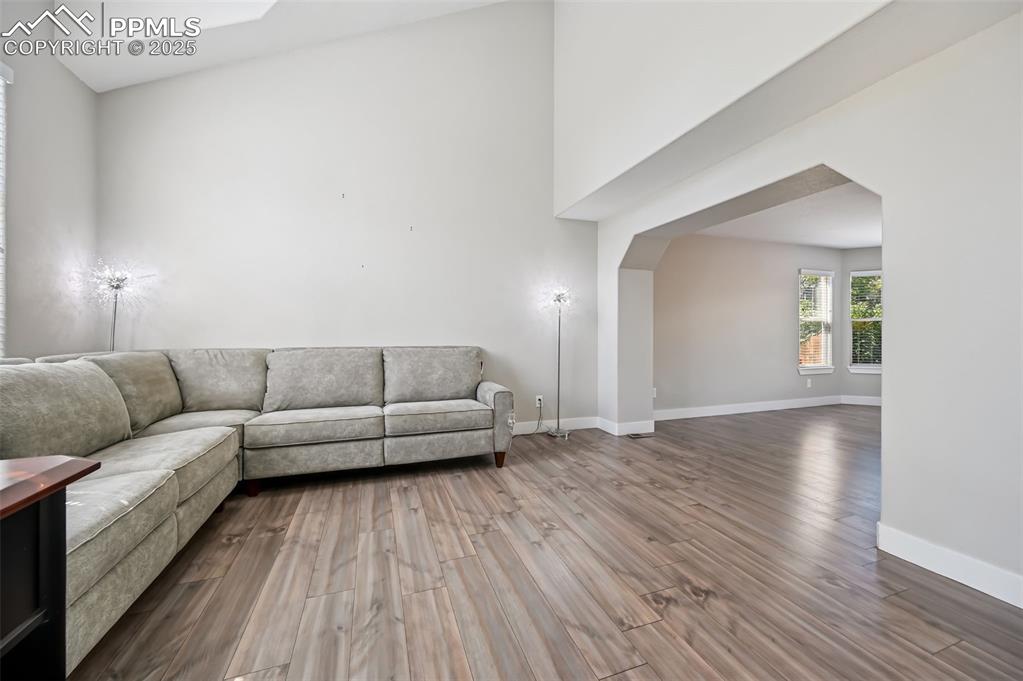 Image 4 of 39: Living area with dark wood-style floors, a high ceiling, and arched walkway