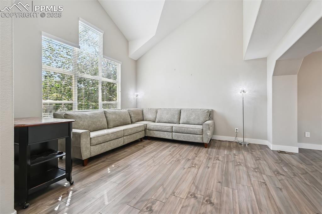 Image 5 of 39: Living area with high vaulted ceiling and wood finished floors